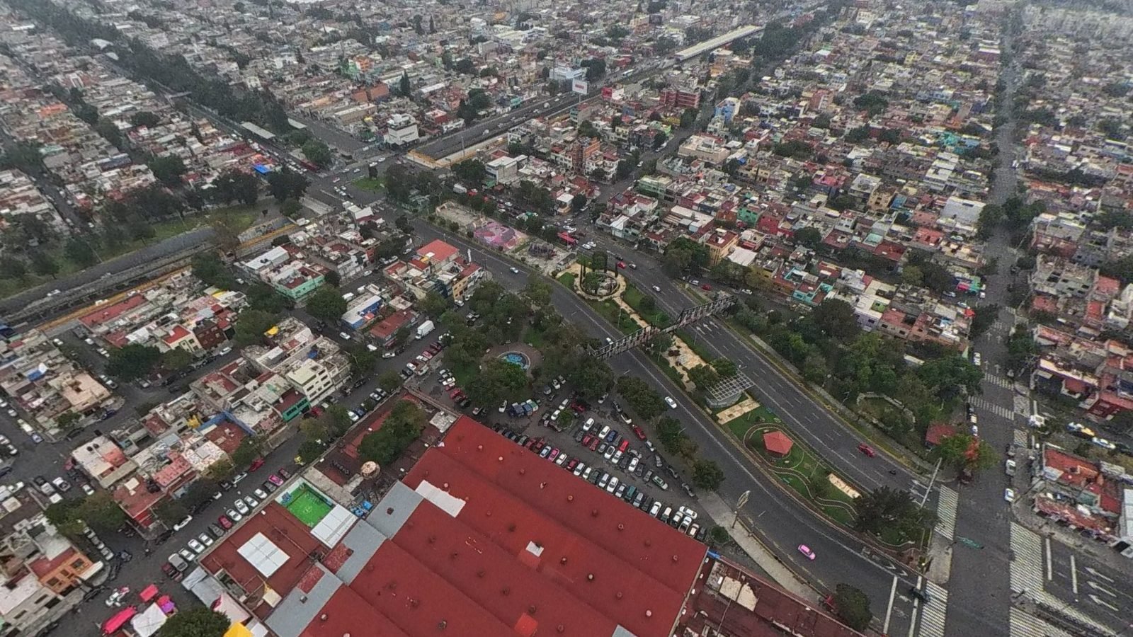 Vista aérea del Mercado del Rastro tomada con dron: la nave de techo rojo, el estacionamiento y la plaza con su fuente